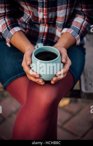 Une femme tenant une tasse de thé dans le parc. Banque D'Images