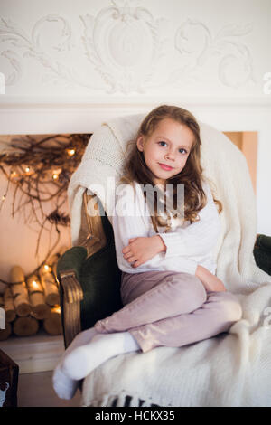 Little girl sitting on cosy enveloppé dans une couverture de l'arbre de Noël président matin à Accueil Banque D'Images