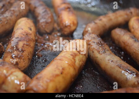 La cuisson des saucisses juteuses sur un carter en fonte de fer chaud close-up view Banque D'Images