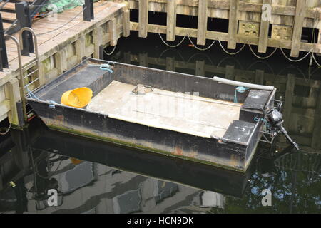 Bateau de travail sur l'eau peu profonde avec clôture en bois entourant Banque D'Images