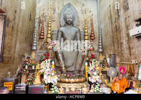Statue d'un bouddha sculpté dans la pierre noire dans la posture européenne , assis sur une chaise, les mains sur les genoux et les deux pieds sur le sol, dans Ayuttha Banque D'Images