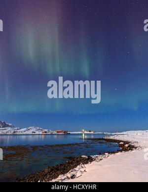 Northern Lights sur les pistes enneigées reflète dans le froid, la mer, Volanstinden Fredvang, îles Lofoten, dans le Nord de la Norvège Banque D'Images