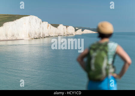 Une femme regarde vers les Sept Soeurs en marchant dans les South Downs Way, Parc National des South Downs, East Sussex, UK Banque D'Images