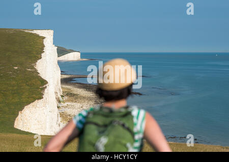 Une femme donne sur les falaises avec vue sur les Sept Soeurs de côte, le Parc National des South Downs, East Sussex, UK Banque D'Images