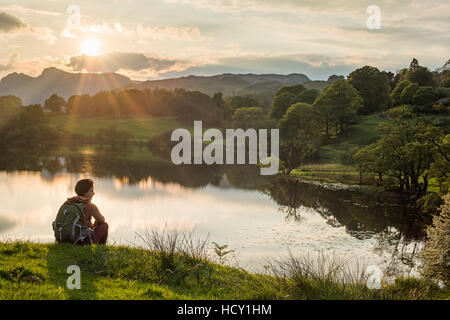 Une femme donne sur Loughrigg Tarn près de Ambleside, Parc National de Lake District, Cumbria, Royaume-Uni Banque D'Images