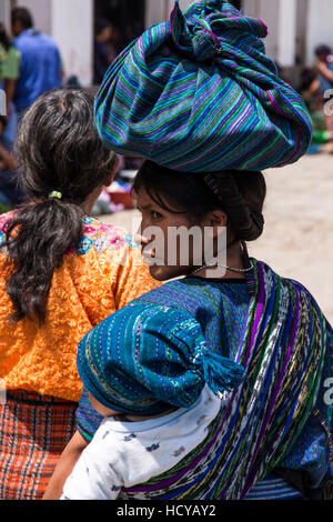 Une jeune femme maya dans l'habit traditionnel de San Antonio Palopo, Guatemala, porte son bébé sur son dos dans un tzute ou utilitaire. Elle est location Banque D'Images