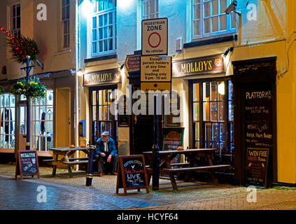 Senior man sitting outside Molloys pub à Teignmouth, Devon, Angleterre, Royaume-Uni Banque D'Images