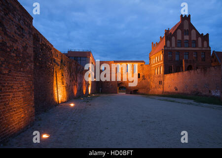 Cour des citoyens par nuit et mur de la ville avec la porte de Torun, Pologne Banque D'Images