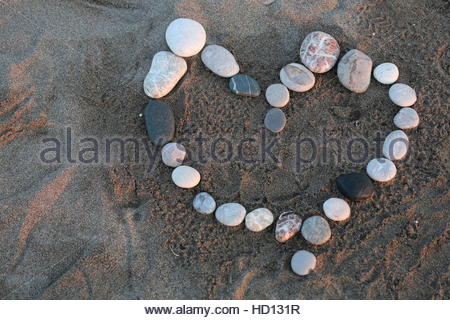 Coeur d'amour de pierre de galets sur une plage comme Rhodes bénéficie d'un magnifique coucher de soleil Banque D'Images