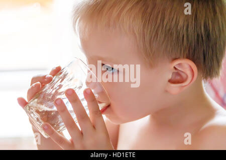 Photo de l'eau potable à partir de l'enfant blond glass Banque D'Images