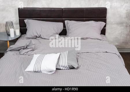 Close up of lit élégant avec des couleurs grises et table de chevet avec des bougies Banque D'Images