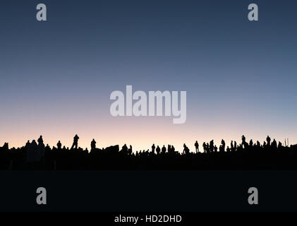 Les touristes et les habitants silhouetté contre l'aube à la lumière témoin sunrise de sommet du volcan Haleakala, Maui, Hawaii. Banque D'Images