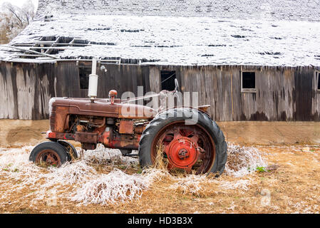 Vieux tracteur antique recouverte de glace avec une grange couverte de neige près de Burrton, Kansas Banque D'Images