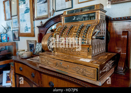 Caisse enregistreuse antique en or avec l'ensemble de marque nationale et du tiroir-caisse de la manivelle sur le côté sur l'affichage sur le bureau en bois ancien Banque D'Images