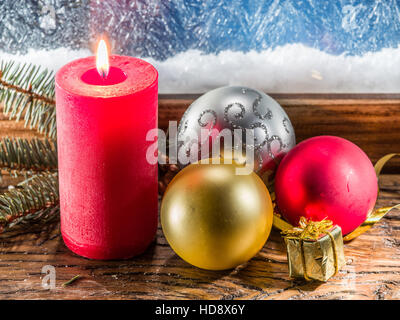 Bougie de Noël, des boules de Noël et congelé fenêtre sur l'arrière-plan. Banque D'Images