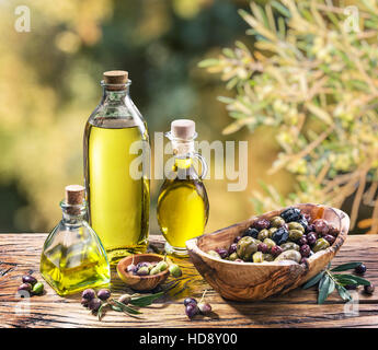 L'huile d'olive et de baies sont sur la table en bois sous l'olivier. Banque D'Images