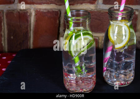 L'eau saine pour les enfants avec de la glace, citron, citron vert, graines de grenade et de pailles. Banque D'Images