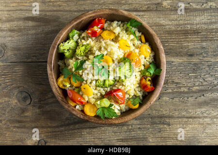 Des délicieux plats végétariens bulgur (couscous) avec des légumes : tomates, carottes, courgettes, brocoli et le persil dans un bol en bois rustique - veg Banque D'Images