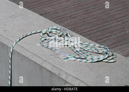 La ligne d'amarrage enroulée autour d'un taquet sur le quai en bois. Banque D'Images