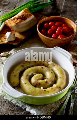 Saucisse au four fait maison avec des pommes de terre et bacon sur un fond rustique. Banque D'Images