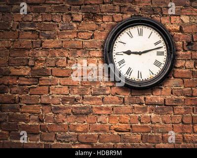 Vintage Horloge Station sur un mur de brique rouge Banque D'Images