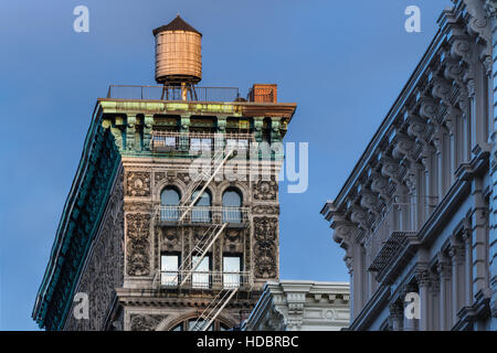 Bâtiment Soho avec terracotta ornementation, corniche, d'un escalier de secours et tour de l'eau éclairée par la lumière au coucher du soleil. New York City Banque D'Images