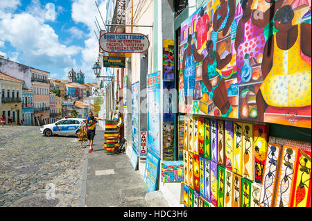 SALVADOR, BRÉSIL - 12 mars 2015 : Un vendeur de rue se trouve à l'extérieur des magasins vendant des souvenirs touristiques afro-brésilien dans le Pelourinho. Banque D'Images