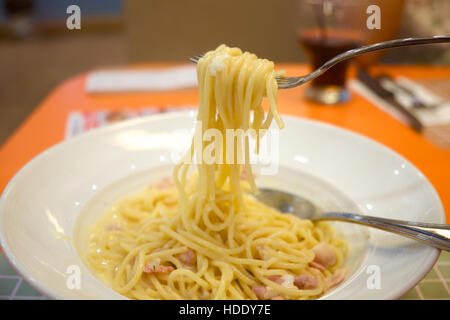 Spaghetti carbonara sur la plaque blanche roula sur la fourche à l'arrière-plan flou Banque D'Images