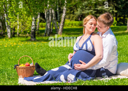 Aimer les jeunes couple expecting a baby, reste sur un pique-nique dans le parc Banque D'Images