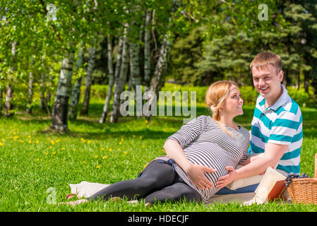 Femme enceinte avec son mari sont situés sur le parc à l'été à carreaux Banque D'Images