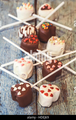 Beaucoup de Cake Pops dans la forme coeur se trouvent sur l'ancien bleu fond de bois vue d'en haut. Banque D'Images