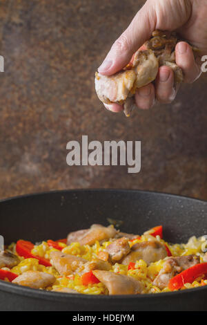 L'ajout de poulet noir dans la casserole avec le riz et le poivron à la verticale Banque D'Images