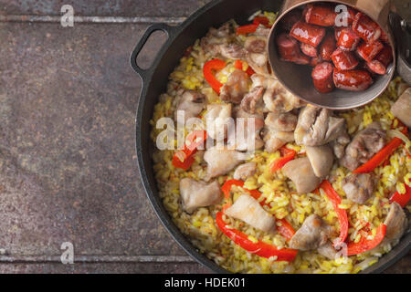 Ajouter les saucisses fumées sur le plateau avec la cuisson de la paella vue supérieure Banque D'Images