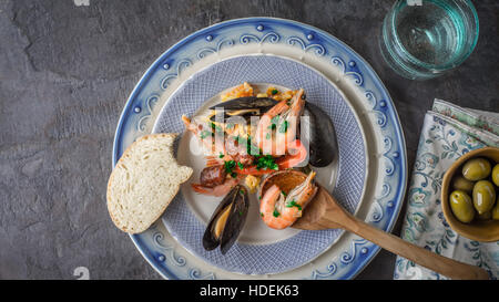 La plaque avec la paella sur la table en pierre sombre avec différents accessoires vue d'en haut Banque D'Images