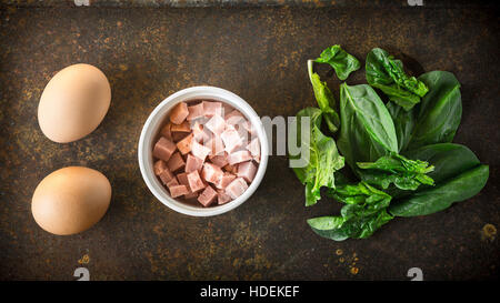 Ingrédients pour les oeufs Florentine aux épinards sur le fond rouillé Banque D'Images