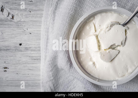 Fromage frais avec cuillère et serviette sur la vue de dessus de table en bois blanc Banque D'Images