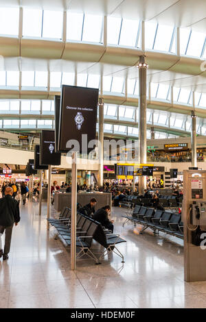 Londres, l'aéroport de Heathrow, Terminal 2. Intérieur La salle de départ. Ligne d'affichage vidéo sur les stands par coin salon certaines personnes. La journée. Banque D'Images