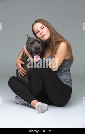 Belle fille avec Stafford Terrier gris Banque D'Images