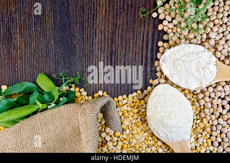 Pois chiches et farine de pois chiche dans une cuillère, cosses vertes sur fond de toile sur planche de bois Banque D'Images