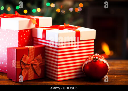 Cadeaux de Noël sur table en bois contre une cheminée. Concept de vacances d'hiver Banque D'Images