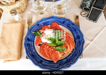 Insalata Caprese (CAPRI) Salade de tomates, mozzarella et basilic. Servi sur une plaque en céramique bleu et blanc. Banque D'Images