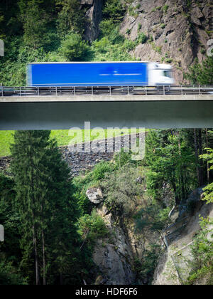 Un chariot est conduite sur un pont routier de l'autoroute suisse A2 vers le tunnel du Gothard à travers les Alpes suisses. Banque D'Images