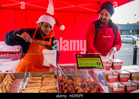 Un homme et une femme à un Sikh détenteurs de décrochage UK Le marché fermier de Noël dessert Sauces au cari et cuit 'vraiment' food indien Banque D'Images