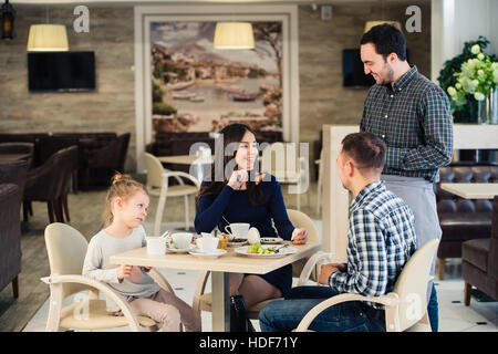 La famille, la parentalité, la technologie, les gens heureux concept - mère, père et petite fille qui a demandé à prendre une photo par serveur smartphone Blackberry Banque D'Images