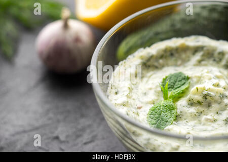 Dans le Tzatziki bol en verre sur la pierre noire table horizontale Banque D'Images