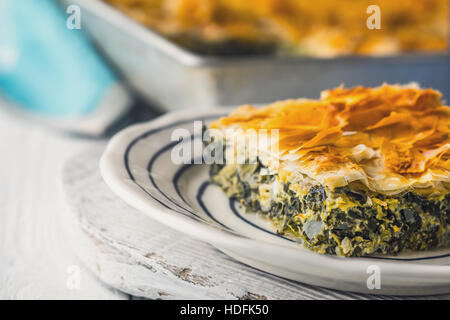 Spanakopita tarte grecque dans la plaque en céramique sur la table horizontale blanche Banque D'Images