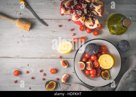 La Grenade aux figues et tomates cerises sur la table en bois blanc Vue de dessus Banque D'Images