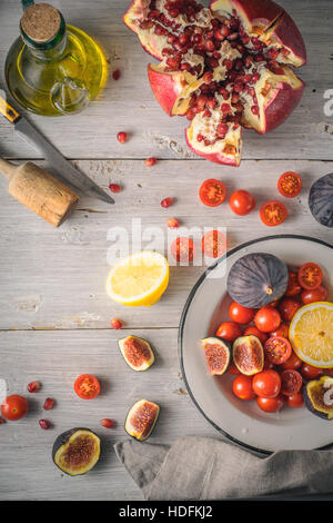 La Grenade aux figues et tomates cerises sur la table verticale en bois blanc Banque D'Images