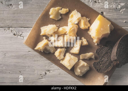 Tranches de pain avec du parmesan sur le parchemin sur la table en bois blanc Vue de dessus Banque D'Images