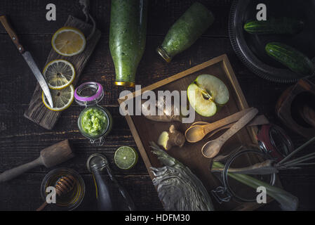 Bouteilles avec différents ingrédients et smoothie vert sur le plateau en bois Vue de dessus Banque D'Images